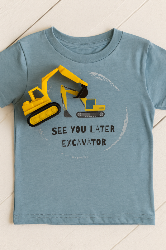 Children's t-shirt with an excavator graphic and text on a tiled floor.